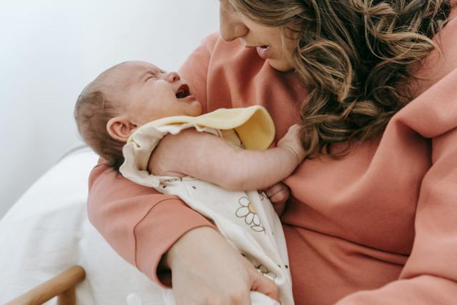 un bébé pleure dans les bras de maman